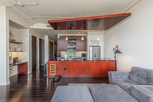 kitchen with pendant lighting, dark wood-type flooring, decorative backsplash, kitchen peninsula, and stainless steel appliances