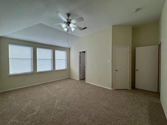 unfurnished bedroom with carpet, ceiling fan, vaulted ceiling, and multiple windows