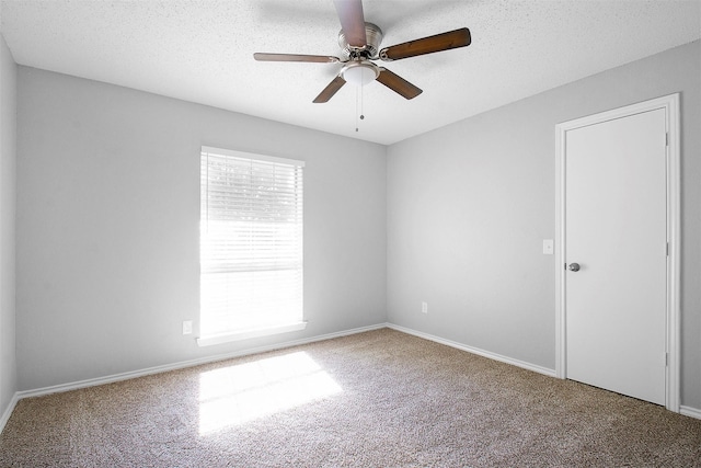 carpeted spare room featuring ceiling fan and a textured ceiling