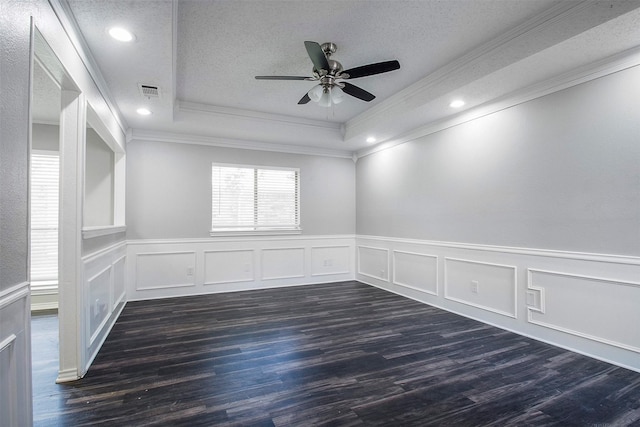 empty room with ornamental molding, ceiling fan, a raised ceiling, dark wood-type flooring, and a textured ceiling