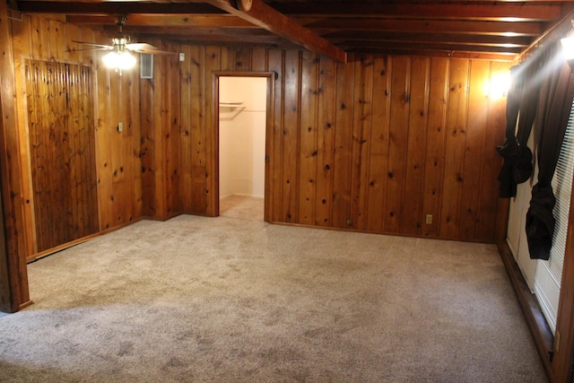 basement with light colored carpet, ceiling fan, and wood walls