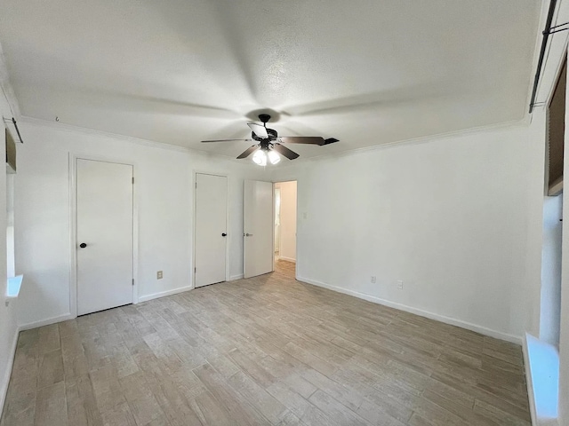 unfurnished bedroom with two closets, light hardwood / wood-style flooring, ceiling fan, and crown molding