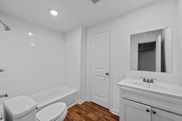 full bathroom featuring hardwood / wood-style floors, vanity, tiled shower / bath combo, and toilet