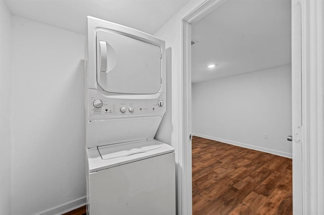 washroom with stacked washer and dryer and dark wood-type flooring