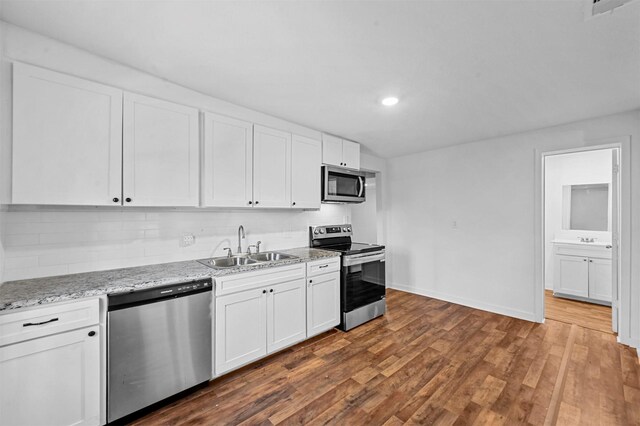 kitchen with white cabinetry, dark hardwood / wood-style flooring, stacked washer / drying machine, and appliances with stainless steel finishes