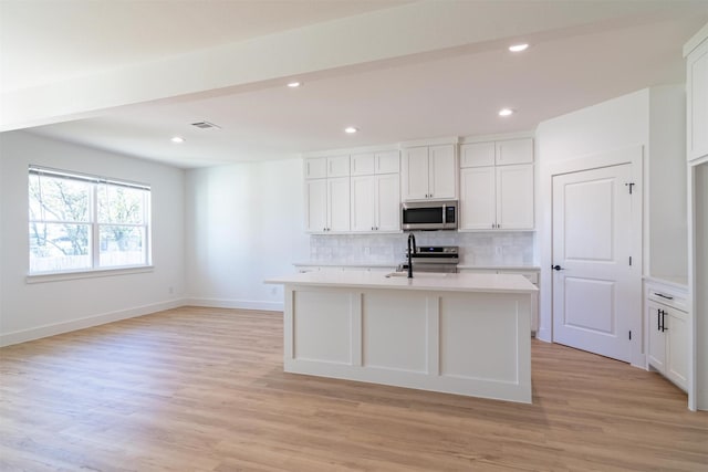 kitchen with white cabinets, light wood-type flooring, and stainless steel appliances