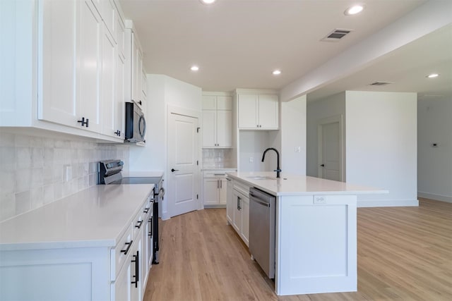 kitchen featuring a kitchen island with sink, sink, white cabinets, and stainless steel appliances