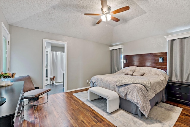 bedroom with wood-type flooring, a textured ceiling, vaulted ceiling, and ceiling fan