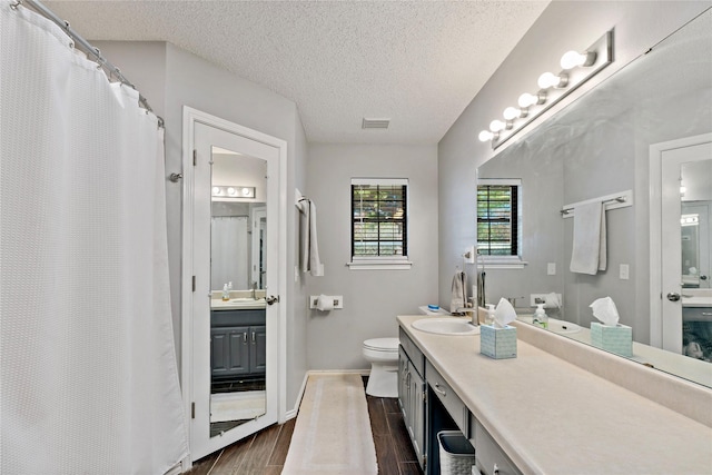 bathroom with vanity, toilet, hardwood / wood-style floors, and a textured ceiling