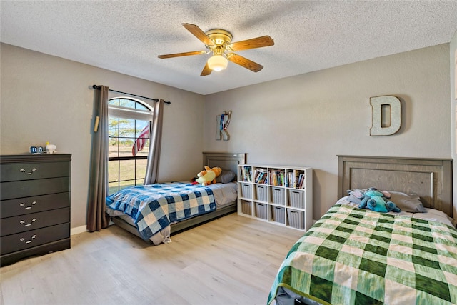 bedroom with ceiling fan, light hardwood / wood-style flooring, and a textured ceiling