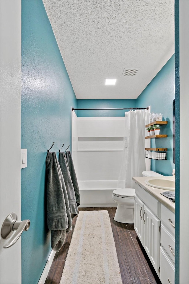 full bathroom with vanity, a textured ceiling, shower / bath combination with curtain, and toilet