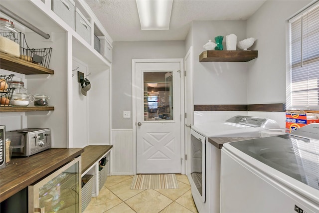 laundry room featuring washing machine and clothes dryer, light tile patterned floors, wine cooler, and a textured ceiling