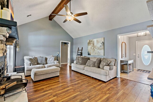 living room featuring ceiling fan, vaulted ceiling with beams, wood-type flooring, a textured ceiling, and a fireplace