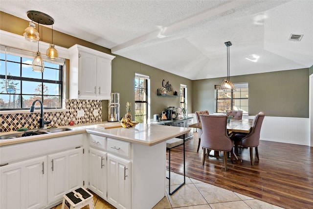 kitchen featuring white cabinetry, a kitchen bar, decorative light fixtures, and sink