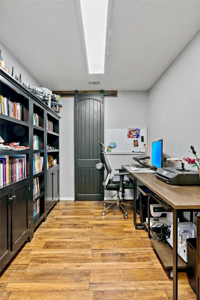 office space featuring a barn door and light hardwood / wood-style flooring