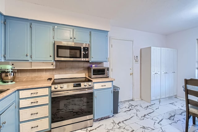 kitchen featuring decorative backsplash, blue cabinets, and appliances with stainless steel finishes