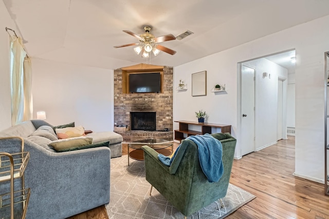 living room featuring a fireplace, vaulted ceiling, light hardwood / wood-style flooring, and ceiling fan