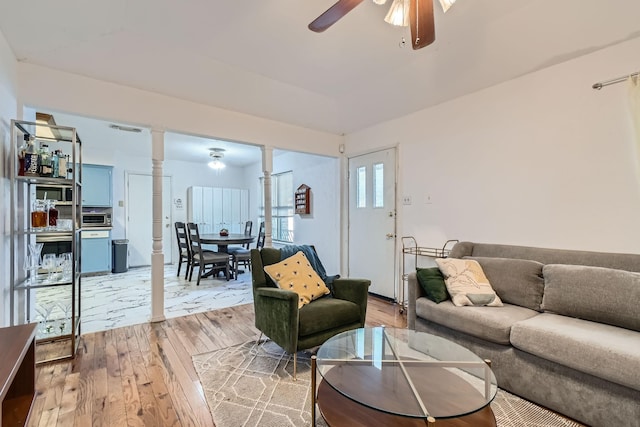 living room with hardwood / wood-style floors, decorative columns, and ceiling fan