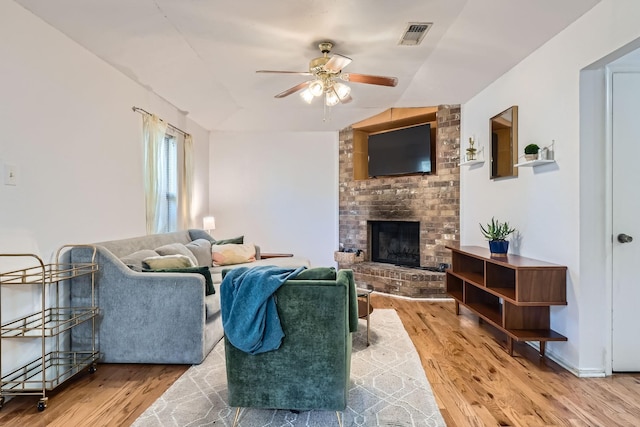 living room featuring wood-type flooring, ceiling fan, and a fireplace