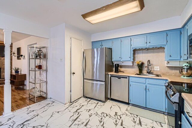 kitchen with backsplash, sink, stainless steel appliances, and blue cabinets