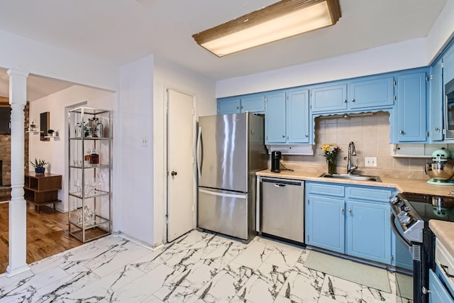 kitchen featuring blue cabinets, tasteful backsplash, appliances with stainless steel finishes, and sink