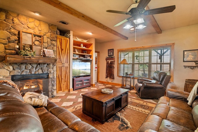 living room with ceiling fan, a stone fireplace, and beam ceiling