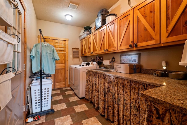 laundry room featuring cabinets, sink, washer and dryer, and a textured ceiling