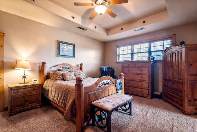 carpeted bedroom with ceiling fan and a raised ceiling