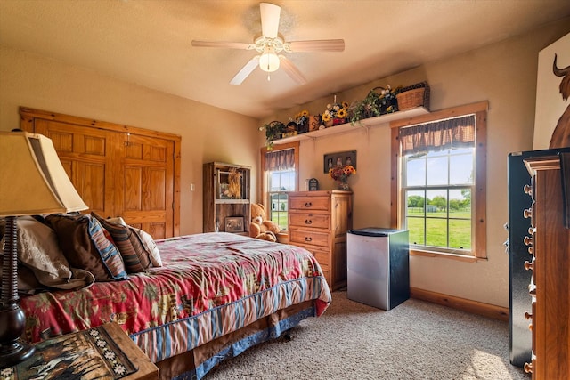 carpeted bedroom with stainless steel refrigerator and ceiling fan