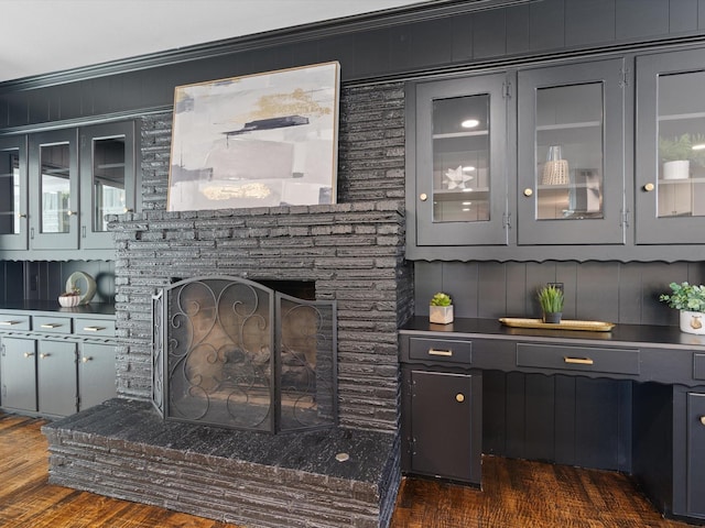 bar with a fireplace, crown molding, and dark wood-type flooring