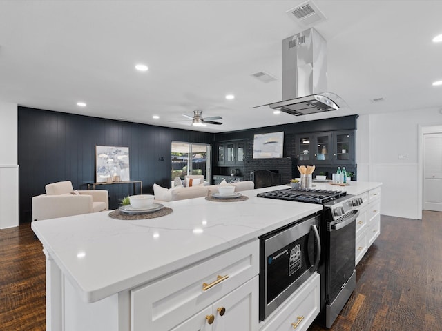 kitchen with island exhaust hood, dark hardwood / wood-style flooring, stainless steel appliances, white cabinets, and a kitchen island