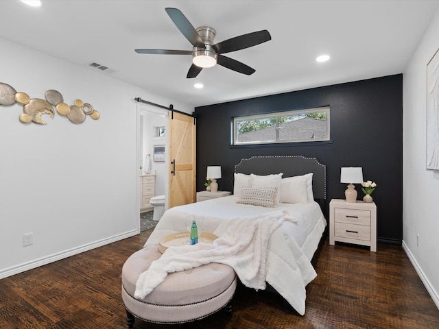 bedroom with a barn door, ensuite bathroom, ceiling fan, and dark hardwood / wood-style floors