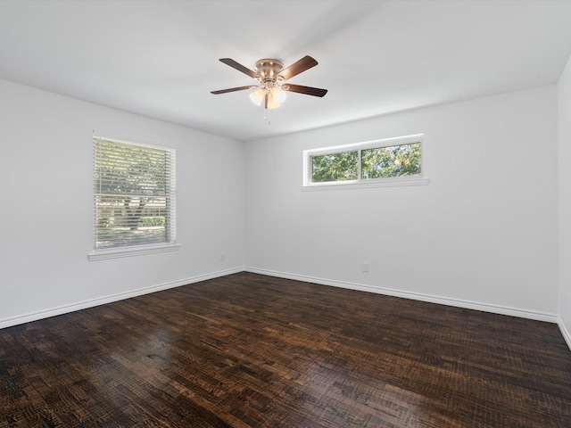 empty room featuring ceiling fan, dark wood-type flooring, and a wealth of natural light