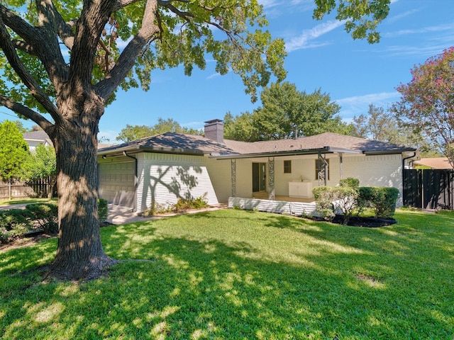 back of house featuring a lawn and a garage