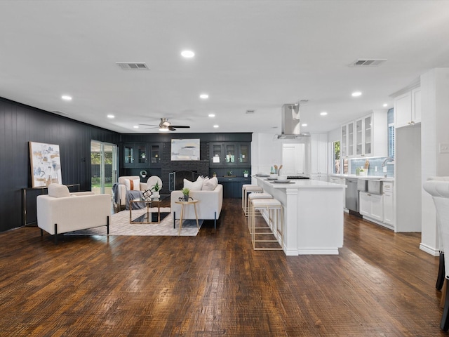 living room featuring dark hardwood / wood-style floors, a brick fireplace, ceiling fan, and a healthy amount of sunlight