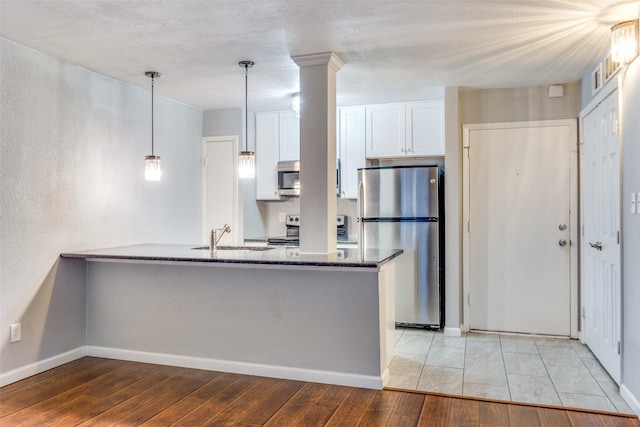 kitchen featuring sink, decorative light fixtures, dark stone counters, stainless steel appliances, and white cabinets