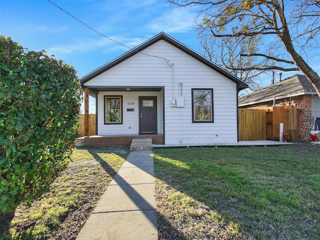 bungalow-style house with a porch, fence, and a front lawn