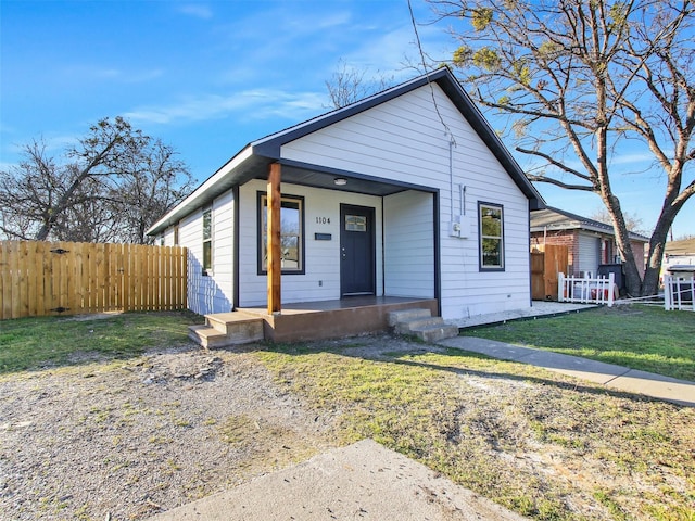 bungalow-style house featuring a porch, a front yard, and fence