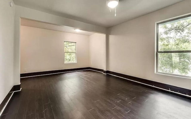 spare room with a wealth of natural light and dark hardwood / wood-style flooring