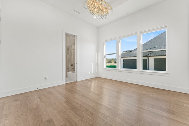 empty room with a chandelier and light hardwood / wood-style flooring