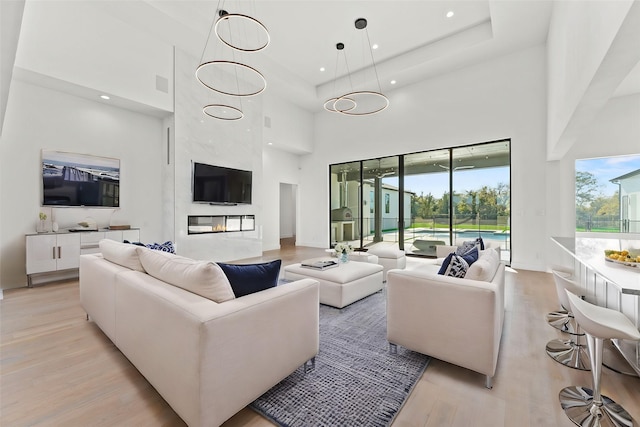 living room featuring a high ceiling, light wood-type flooring, and a premium fireplace