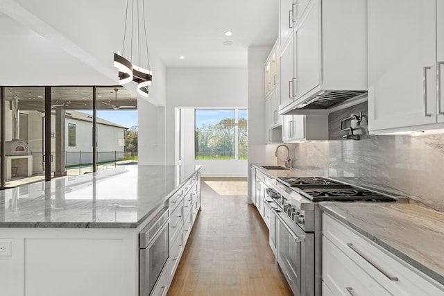 kitchen featuring stainless steel stove, white cabinetry, and light hardwood / wood-style flooring