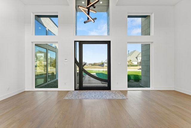 foyer with a notable chandelier, a towering ceiling, and light hardwood / wood-style flooring