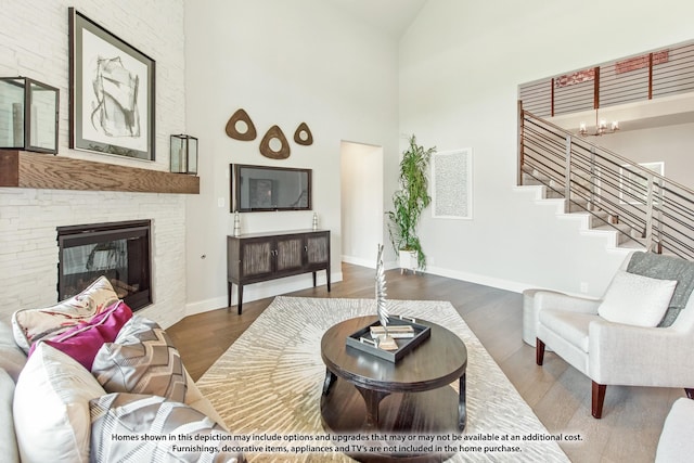 living room featuring a high ceiling, a stone fireplace, dark hardwood / wood-style floors, and a notable chandelier