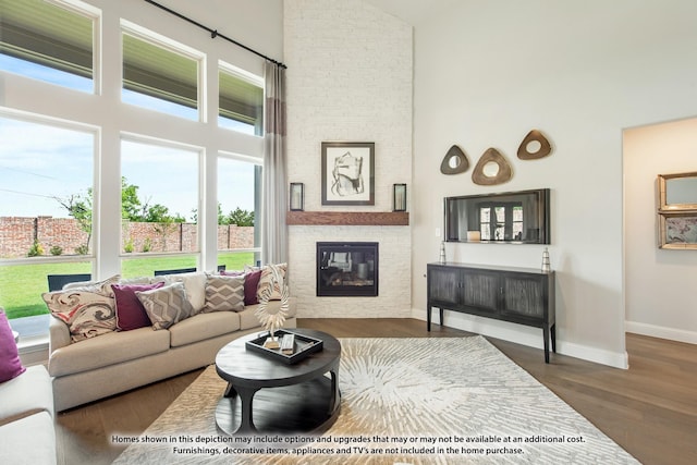 living room with a towering ceiling, dark hardwood / wood-style floors, and a brick fireplace