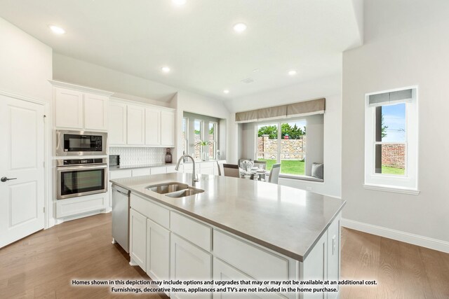 kitchen featuring sink, a center island with sink, appliances with stainless steel finishes, light hardwood / wood-style floors, and white cabinets