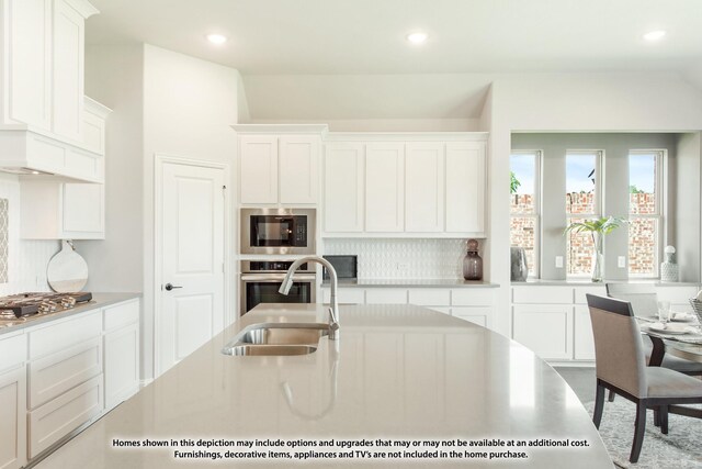 kitchen featuring stainless steel appliances, sink, decorative backsplash, and white cabinets