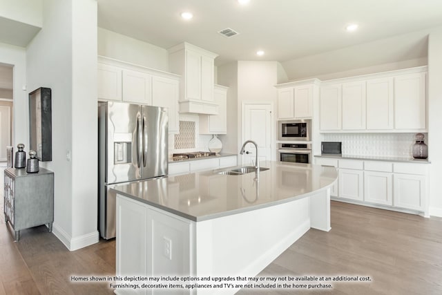 kitchen with a kitchen island with sink, sink, stainless steel appliances, and white cabinets