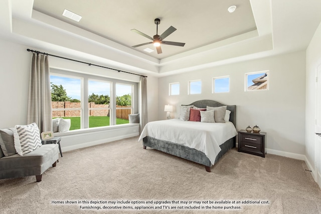 carpeted bedroom with a tray ceiling and ceiling fan