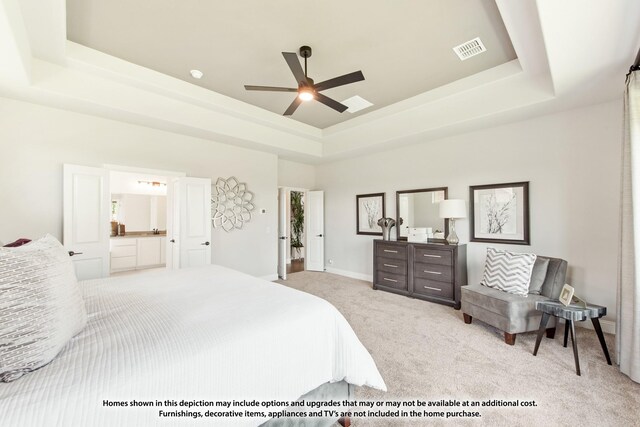 bedroom with ceiling fan, connected bathroom, a raised ceiling, and light carpet